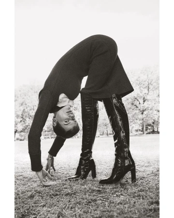 Model bending backwards upside down in a park wearing a dark dress and tall black boots, photographed by Marcus Ohlsson