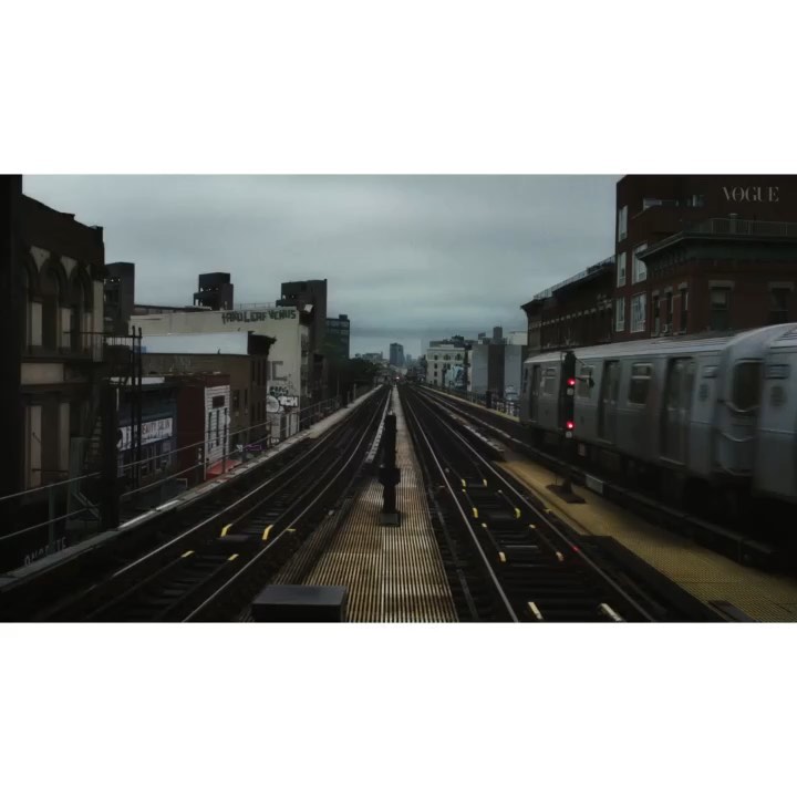 Urban train and tracks with overhead view of buildings and sky, silver passenger train on the tracks in motion, overcast day.