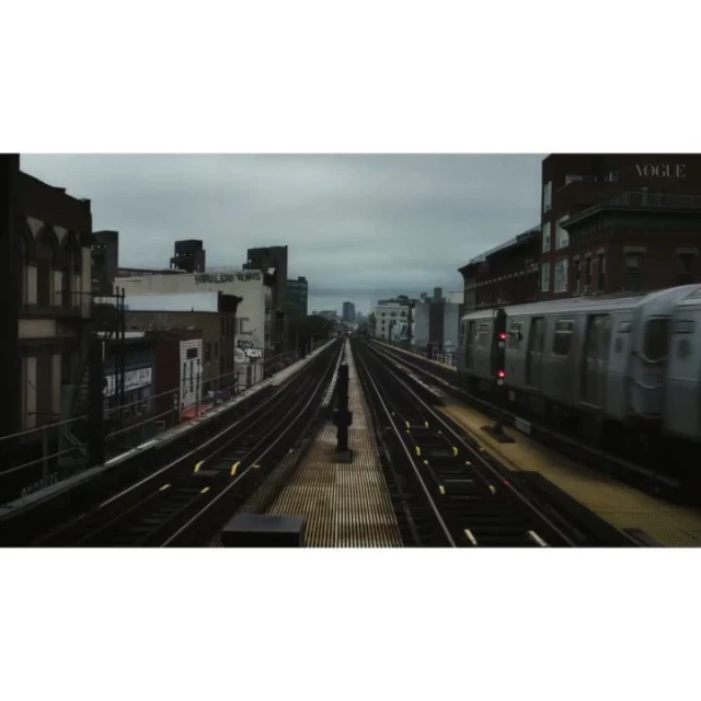 Urban train and tracks with overhead view of buildings and sky, silver passenger train on the tracks in motion, overcast day.