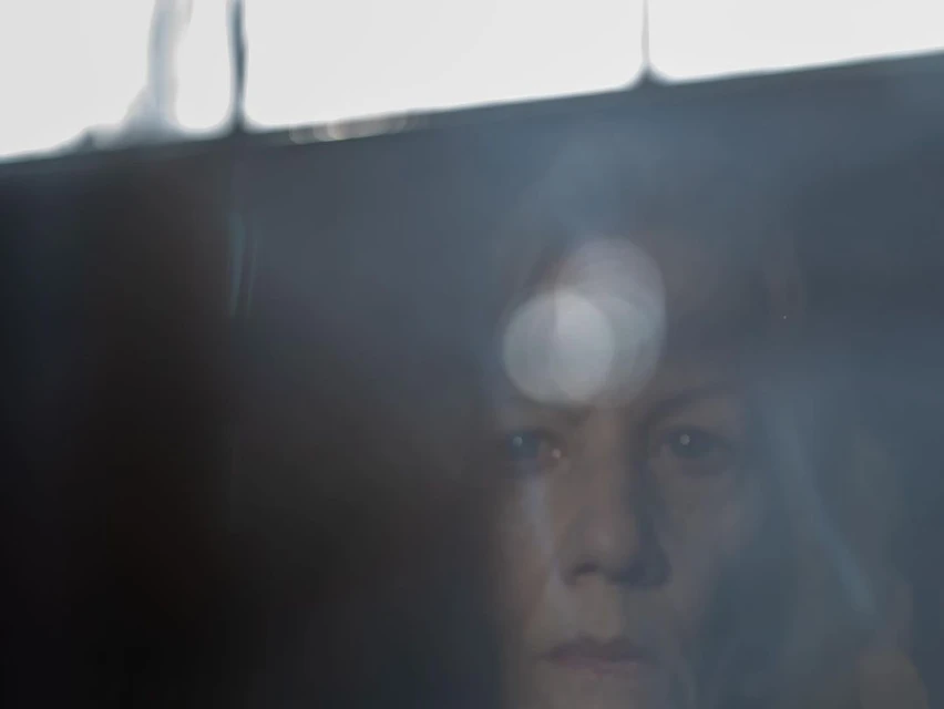 Close-up portrait of an adult woman's face, eyes gazing forward, with an expression of concern and soft, diffused lighting.