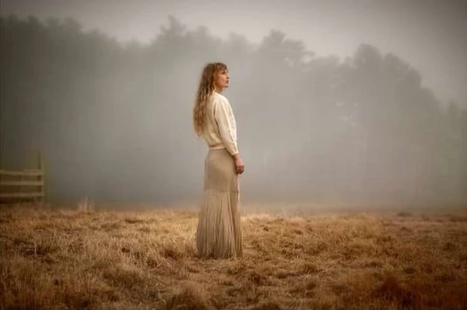Woman with long blonde hair in a cream sweater and skirt standing in a foggy field by Margaret Lampert
