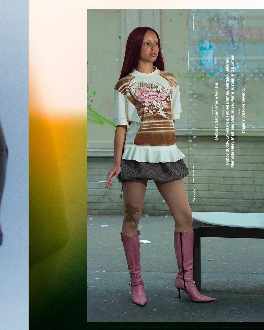 Fashion editorial shot: A young woman with auburn hair poses in a patterned shirt, mini skirt, pink knee-high boots against a graffitied wall.