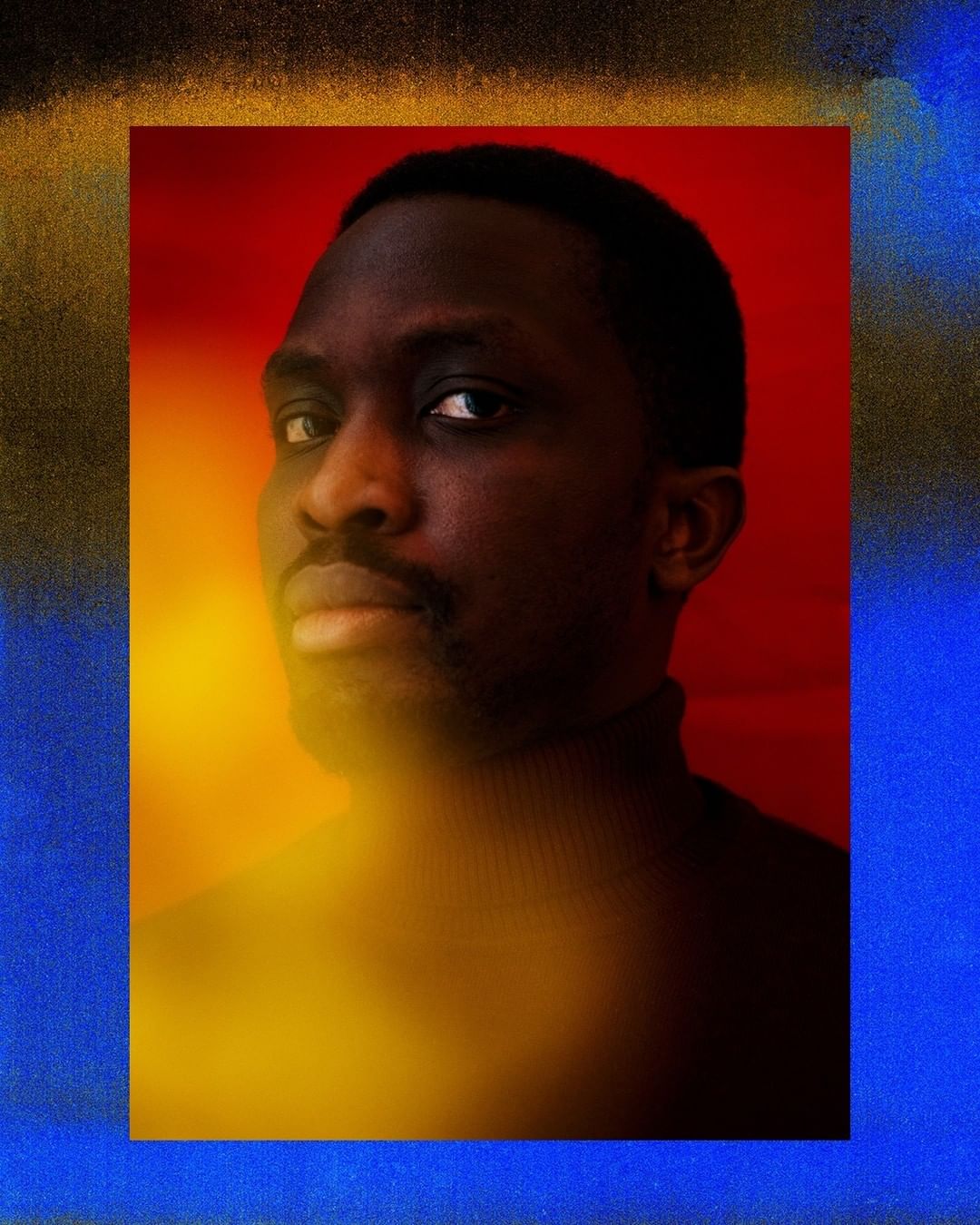 Portrait of a dark-skinned adult male looking at the camera in front of a blended backdrop with red, yellow, and blue hues.
