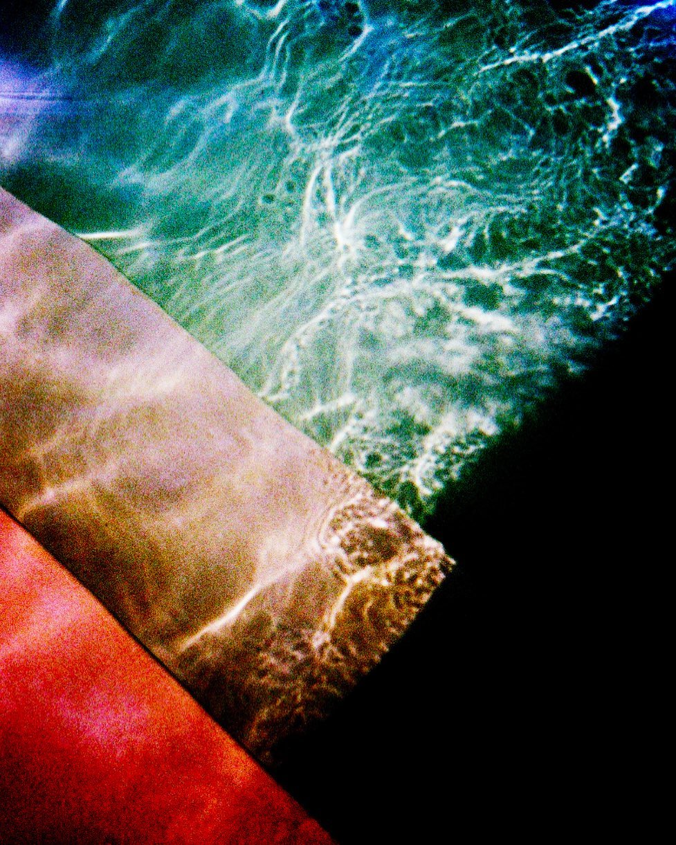 Abstract water surface pattern with sunlight reflections creating a vibrant and colorful display on the water and surrounding surfaces.