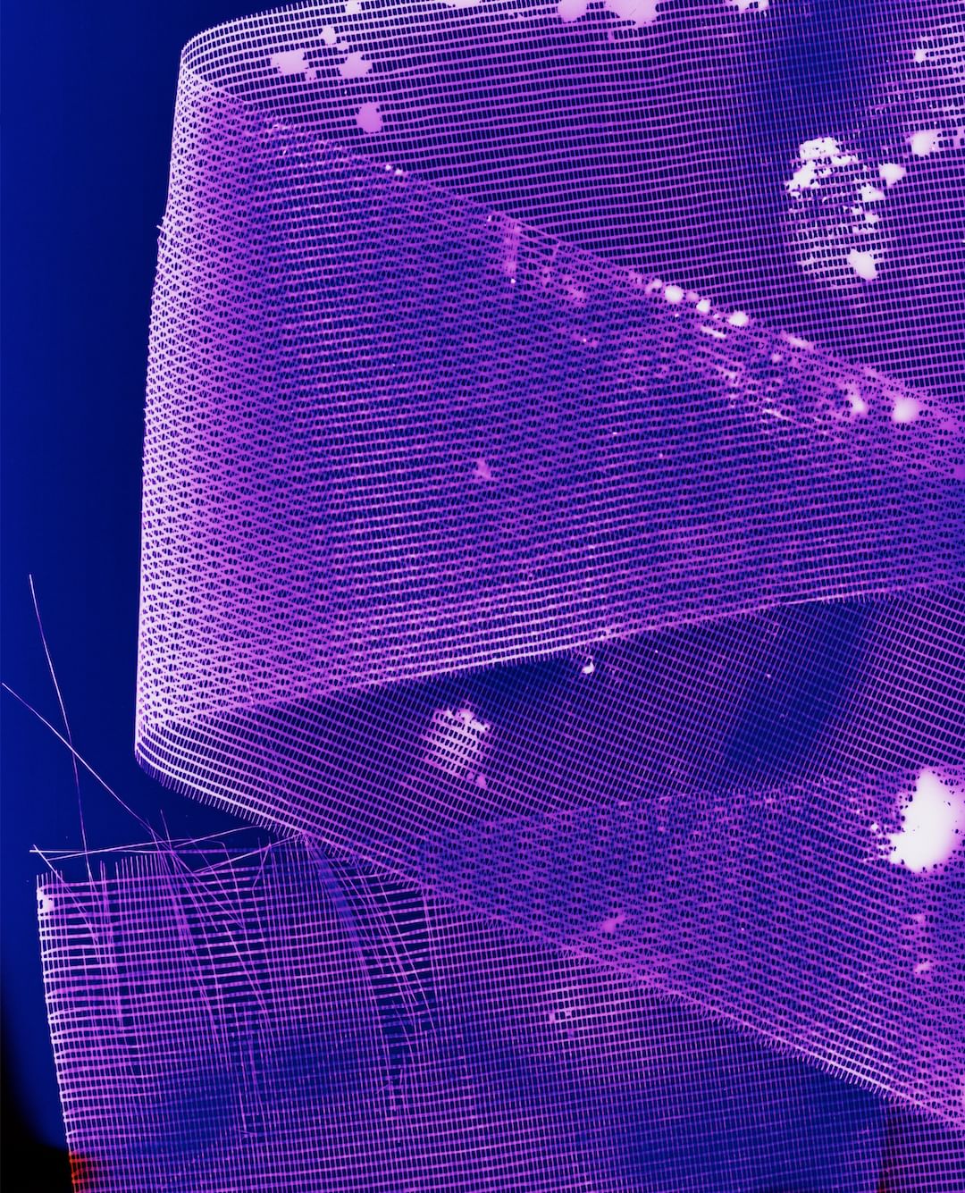 Close-up of a textured, translucent ribbon in shades of blue and purple, displaying intricate grid patterns and subtle white highlights.