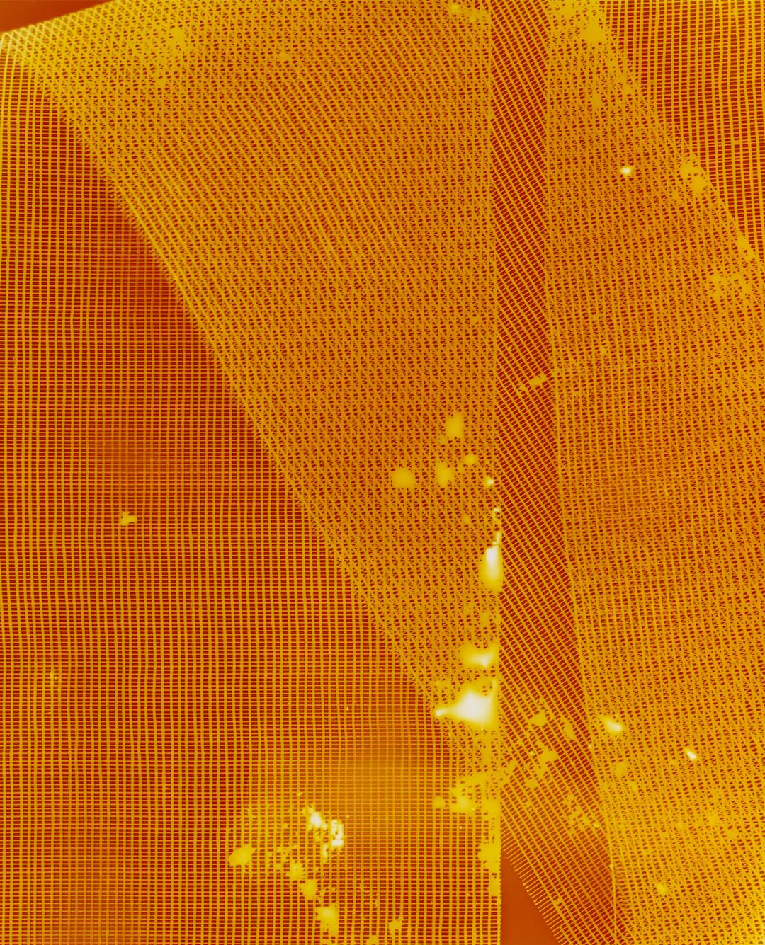 Close-up abstract view of mesh netting material with spots of discoloration, textured surface with a yellow-orange color cast. 