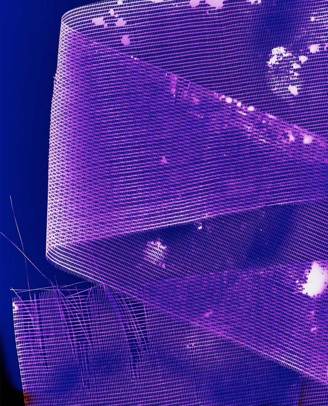 Macro shot of purple wire mesh ribbon abstractly arranged against a dark blue background, creating a textured and colorful pattern.