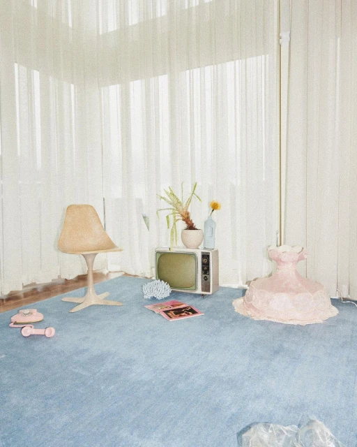 Retro-inspired interior featuring a blue carpet, vintage television, beige chair, pink sculptural form, and sheer white curtains.