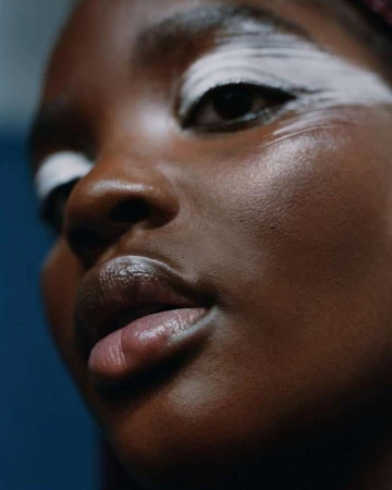 Close-up beauty portrait of a black woman with bold white eye makeup photographed by Maria Del Rio