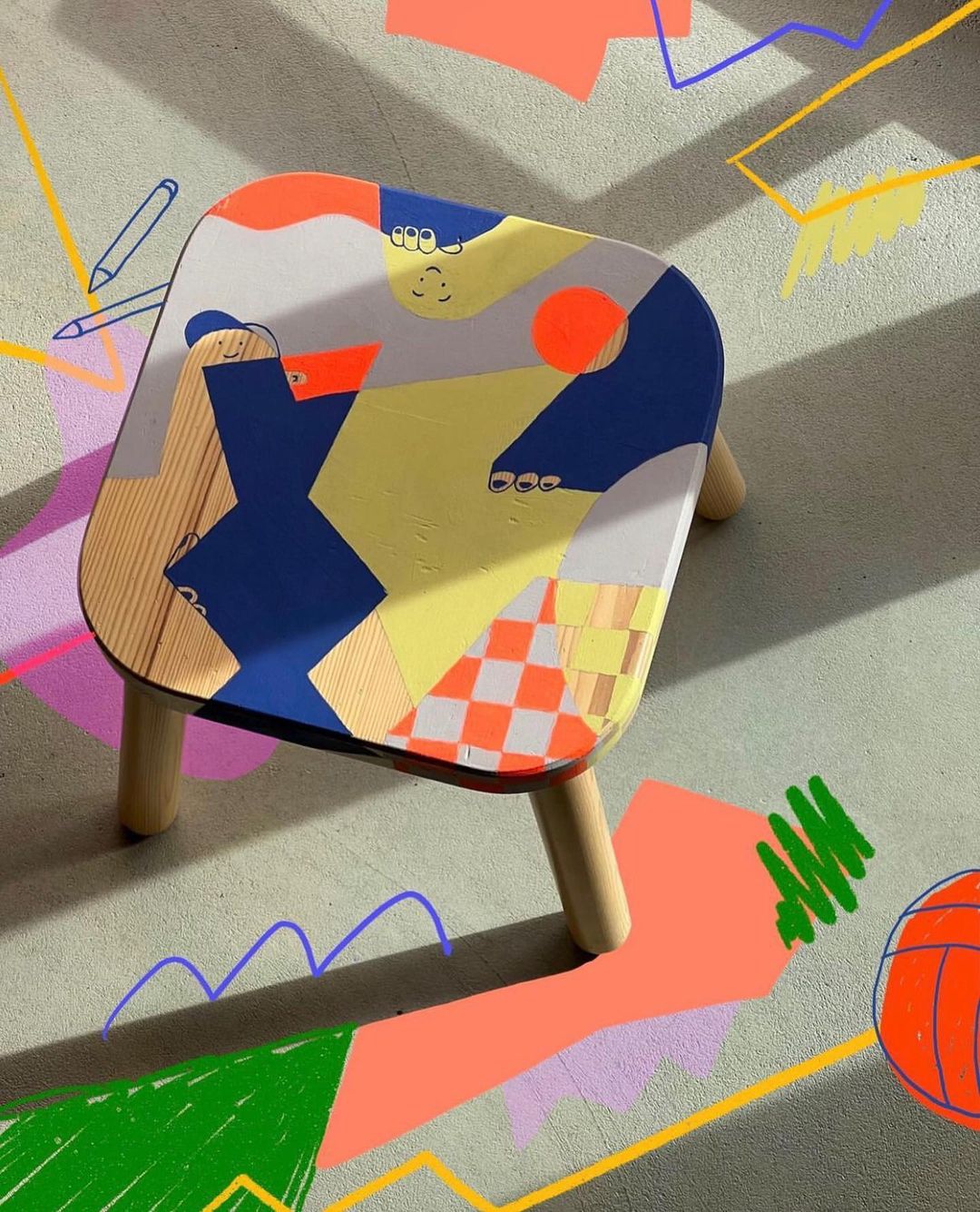 Abstract art-covered children's table on a patterned gray surface. Contemporary design with whimsical drawings and vibrant colors.