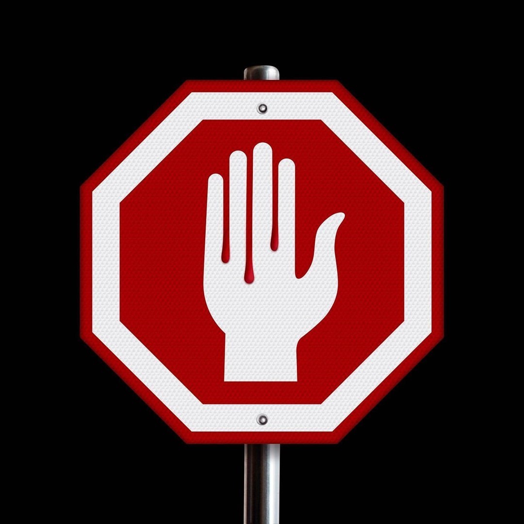 Red octagon sign with white hand symbol on a silver pole against a black background. Warning or prohibition concept.
