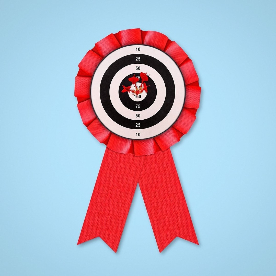 Target award rosette with red ribbon and arrows hitting the bullseye on light blue background, symbolizing accuracy and achievement.