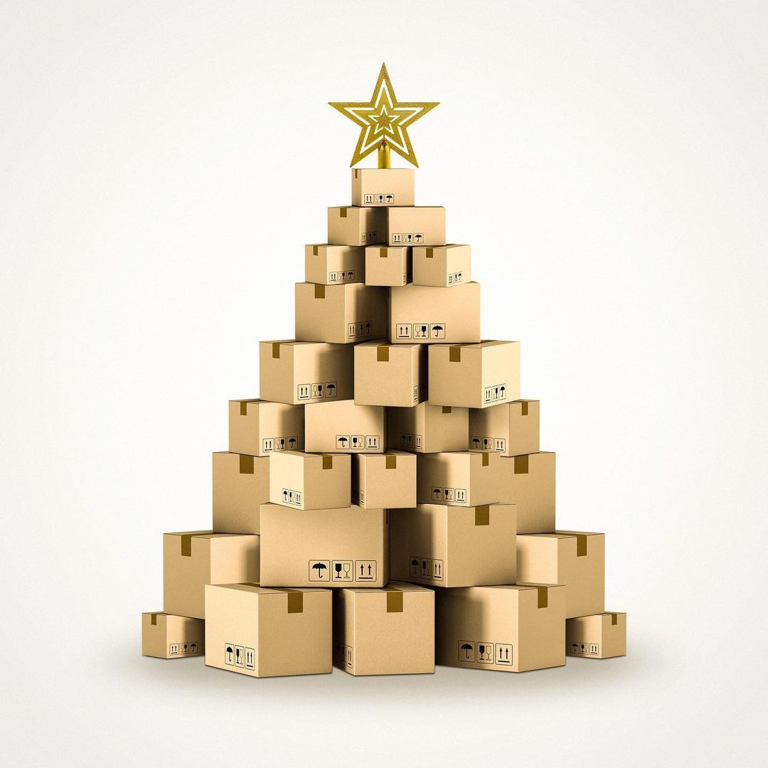 Christmas tree made of stacked cardboard boxes, topped with a golden star, against a plain white background in a studio setting.