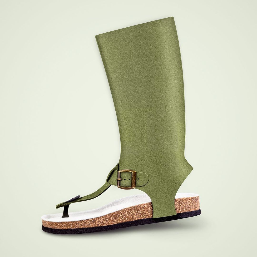 Olive green fashion footwear displaying a sandal fused with a high-top boot, creating a hybrid design on a pale green backdrop.