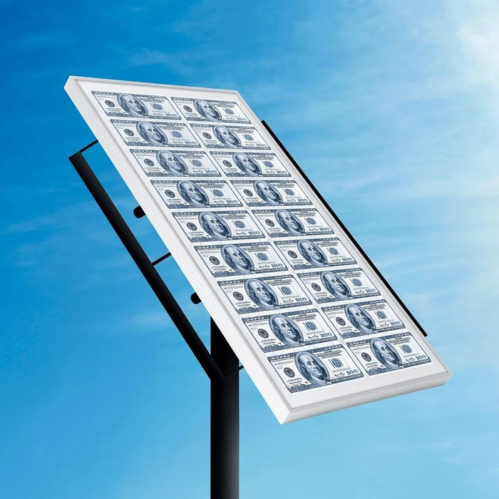 A solar panel surface patterned with US hundred dollar bills angled against a bright blue sky with clouds.