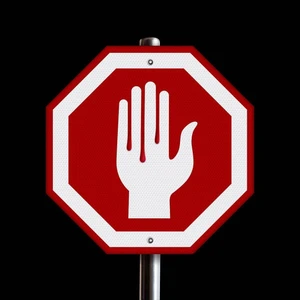 Octagonal red stop sign with a white hand icon on a metal post against a plain black background