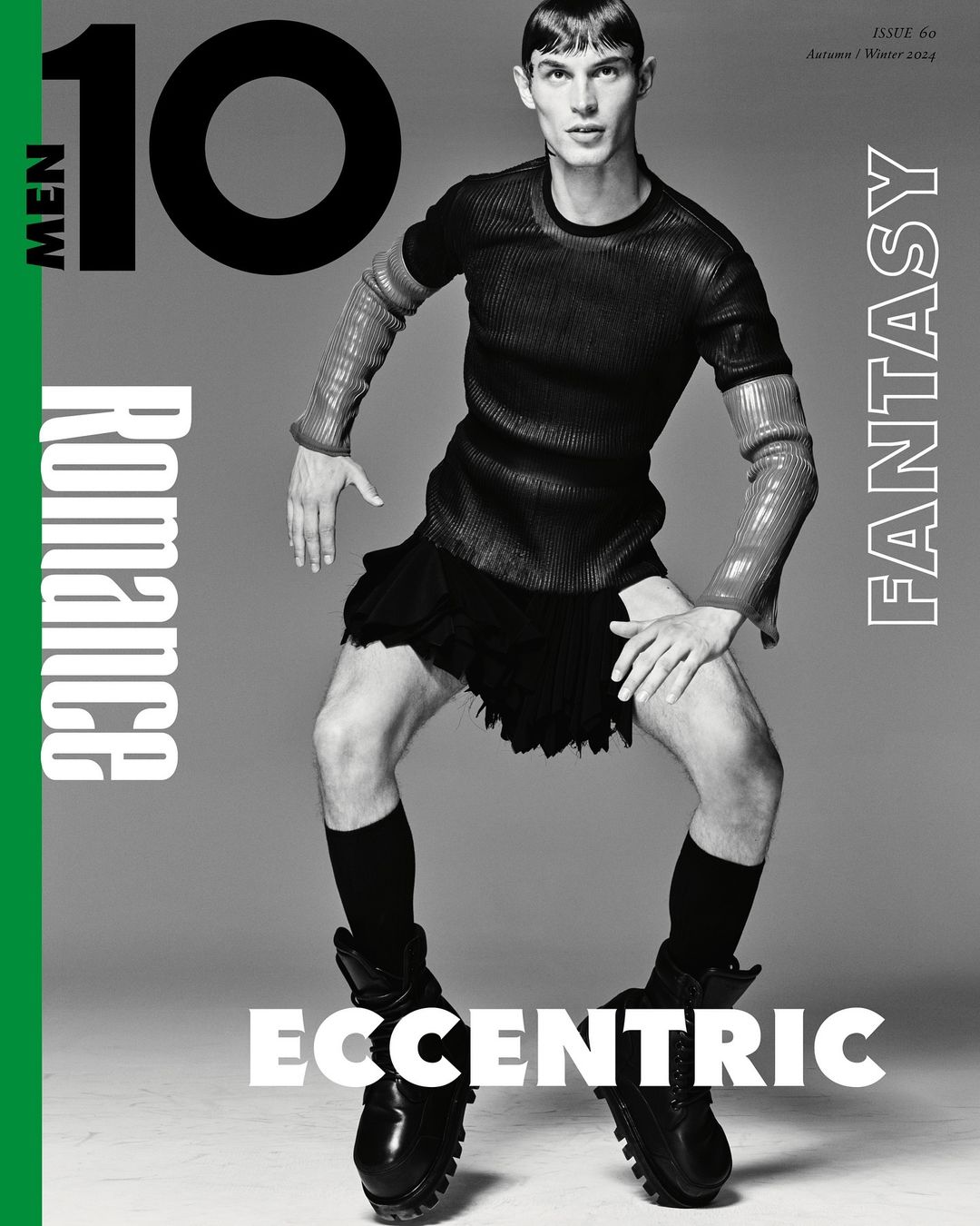 Magazine cover featuring male model in high fashion, wearing a black top, skirt, socks, and boots, set against a grey background.