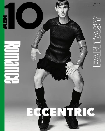 Magazine cover featuring male model in high fashion, wearing a black top, skirt, socks, and boots, set against a grey background.
