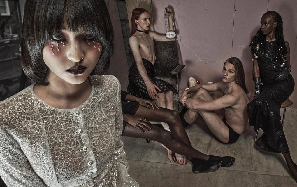 Artistic group portrait of five people in a staged studio setting with textured walls, bold makeup, and dramatic dark fashion.
