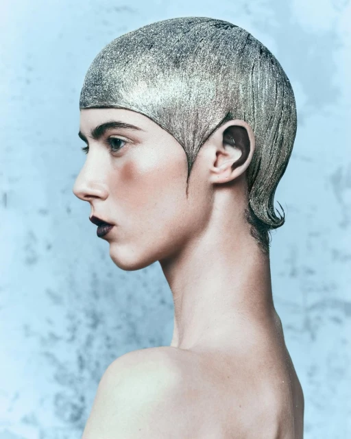 Woman with silver glitter makeup and hairstyle in profile on a light blue background in a beauty or fashion-themed image.