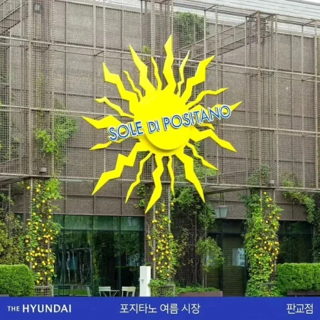Facade of The Hyundai department store featuring a large, yellow sun-shaped sign reading 'SOLE DI POSITANO' above the entrance.