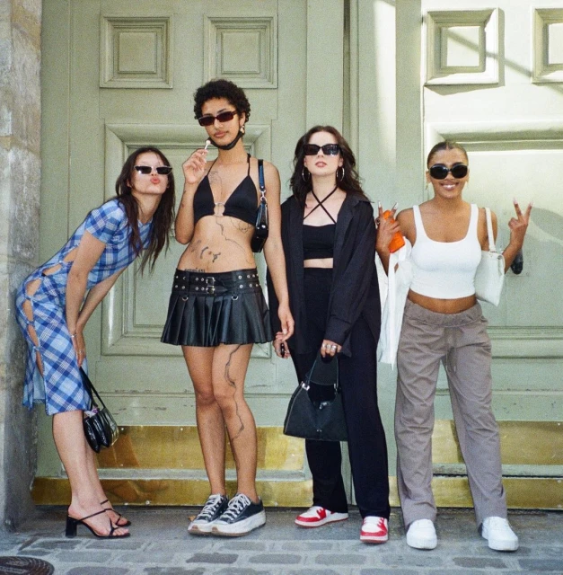 Four young women posing together in front of a classical building door in Paris, captured on analogue film by Marilou Chabert.