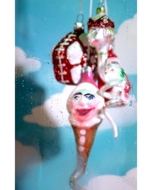 Three vintage glass ornaments hang against a blue cloudy background, one shaped like an ice cream cone and another like an American football.