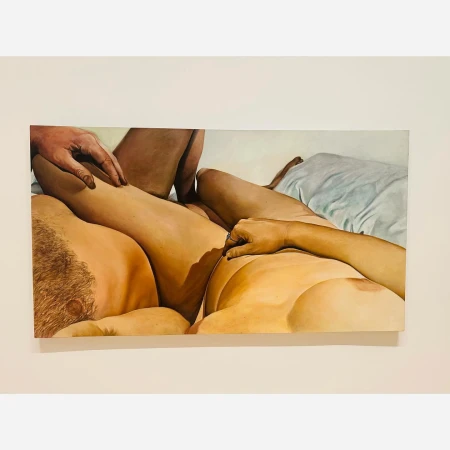 Close-up painted artwork depicting two figures lying down together with visible hands resting on legs against a white wall.