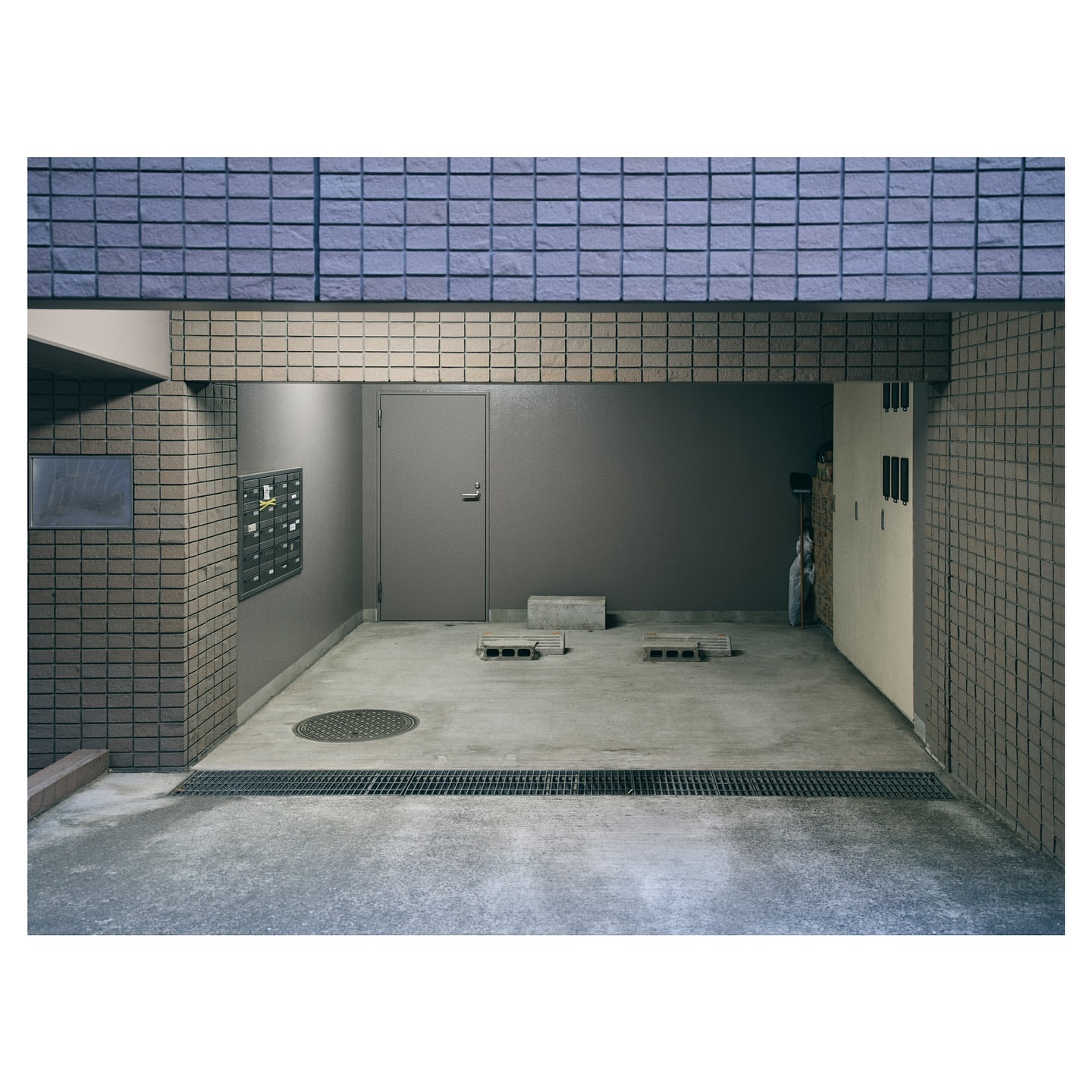An empty parking garage with a closed metal door and blue brickwork, showcasing a quiet, industrial urban architecture scene.