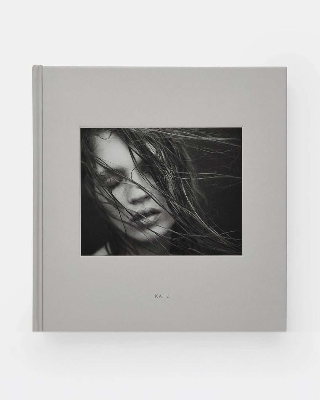 Book cover featuring a black and white portrait of Kate Moss with windswept hair, minimalist design, and soft gray tones.