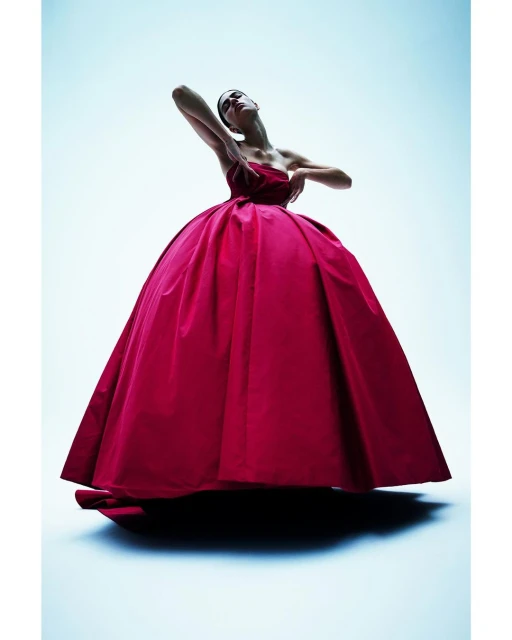 A striking fashion shot features a model in a full, bright pink ballgown, posed against a graduated blue background, under dramatic lighting.