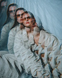 Multiple exposure portrait of a woman wearing tinted sunglasses and a light-colored utility jacket against a crinkled background
