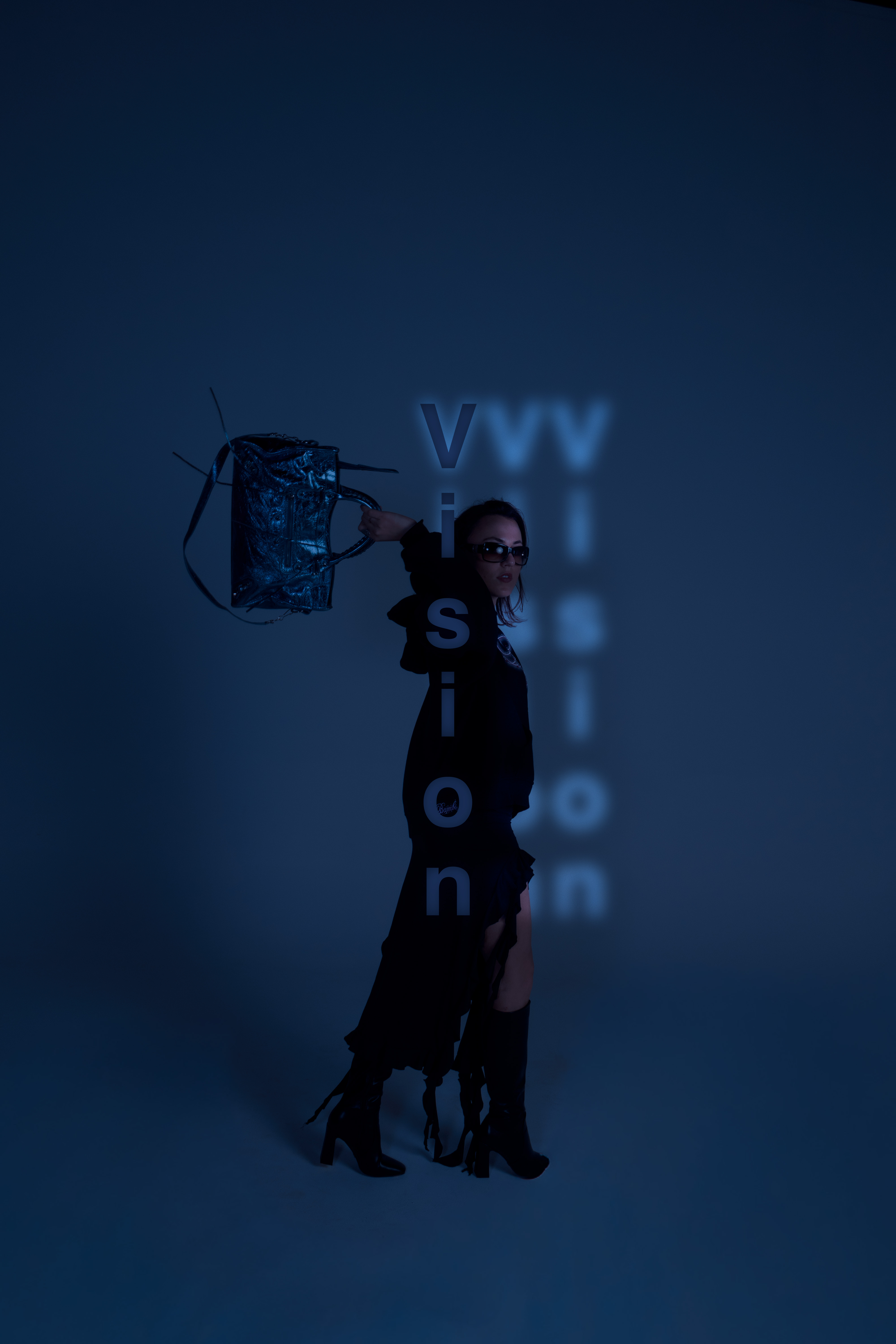 A woman in a black outfit wearing sunglasses holds up a dark handbag against a blue studio background with projected text.