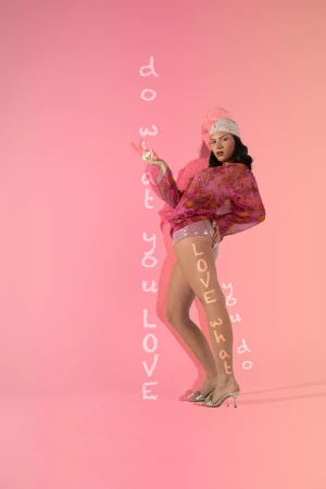 Woman in pink patterned top and headscarf posing against a pink background with overlaid text by Violet Johnston