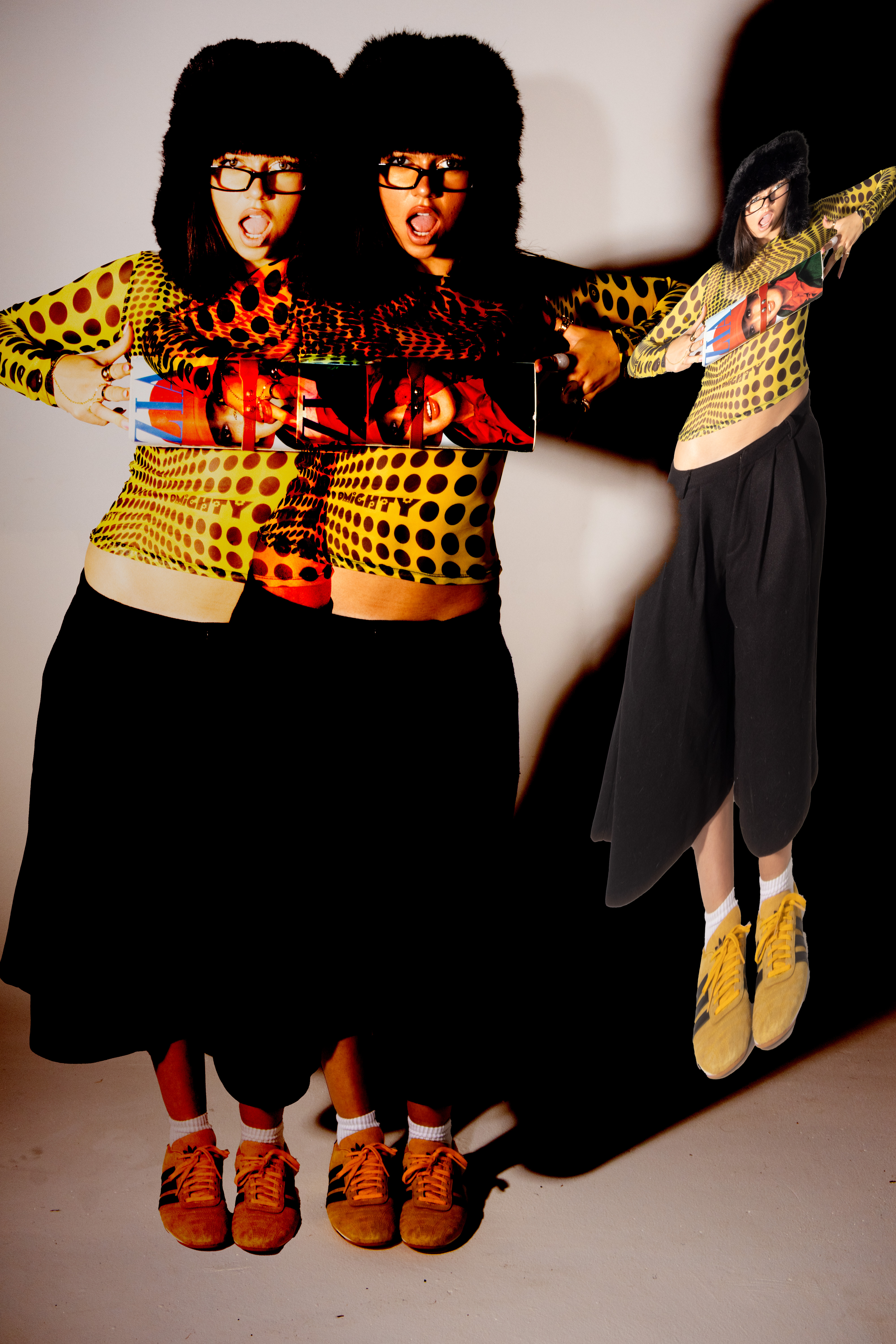 Portrait of a woman wearing black furry hat glasses yellow polka dot top and dark skirt photographed by Violet Johnston