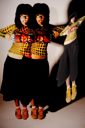 Portrait of a woman wearing black furry hat glasses yellow polka dot top and dark skirt photographed by Violet Johnston