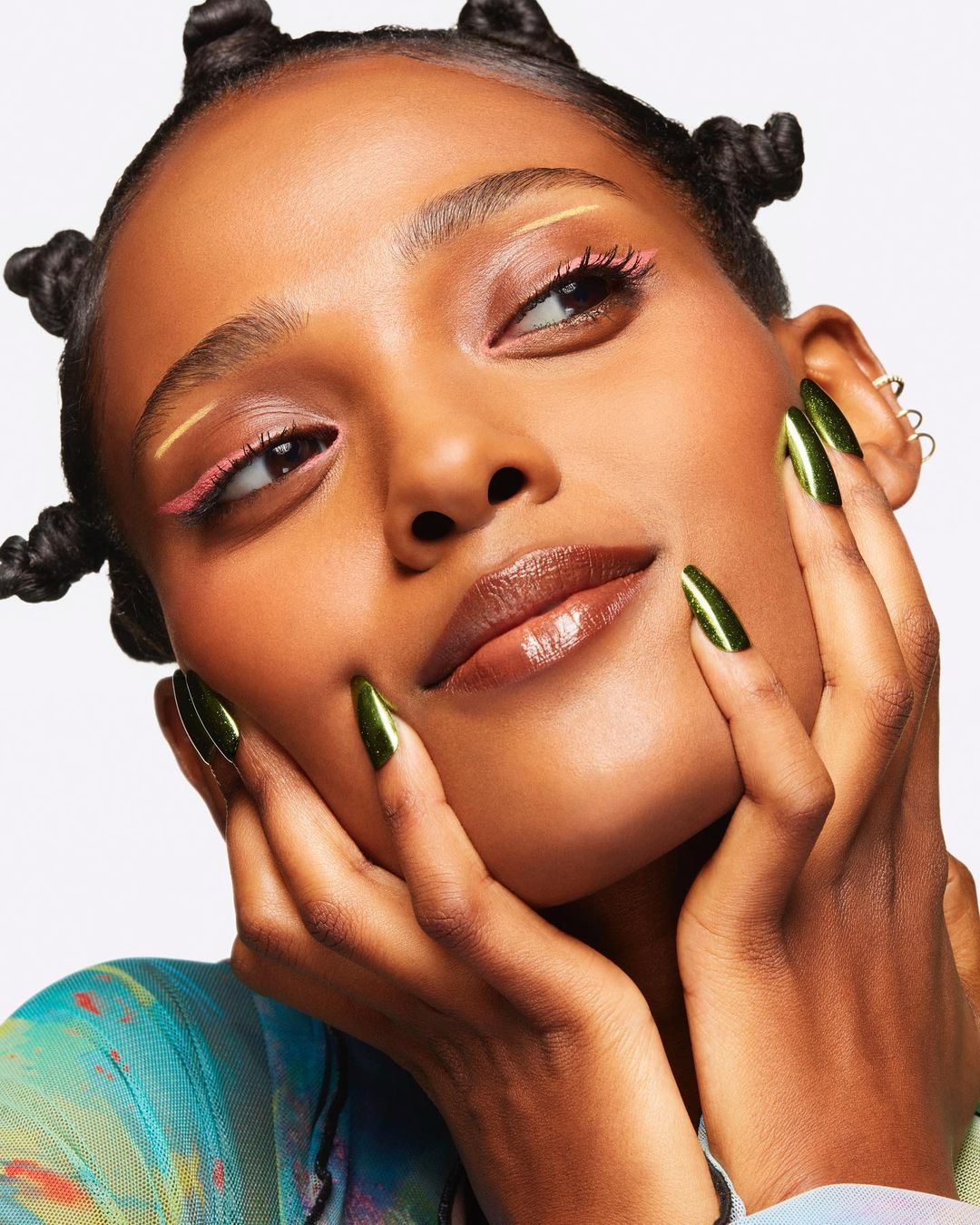 Close-up of a woman with green nails and decorative eyeliner. Beauty shot emphasizing makeup and fashion.
