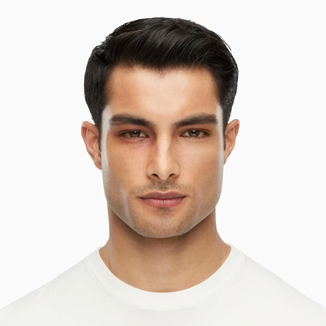 Portrait of an adult male with short dark hair and a white t-shirt, facing the camera, showing a bruise around his left eye.