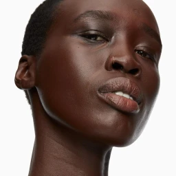 Close-up portrait of a Black woman with short hair and a thin nose ring against a clean white background