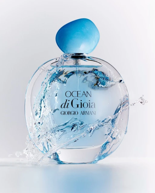 Giorgio Armani Ocean di Gioia perfume bottle, clear glass with a light blue cap, surrounded by splashing water against a white background.