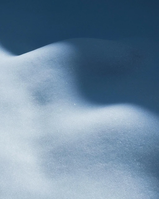 Undulating snowy landscape in soft cool hues, featuring light and shadow play on snow drifts and mounds, in a minimalistic composition.