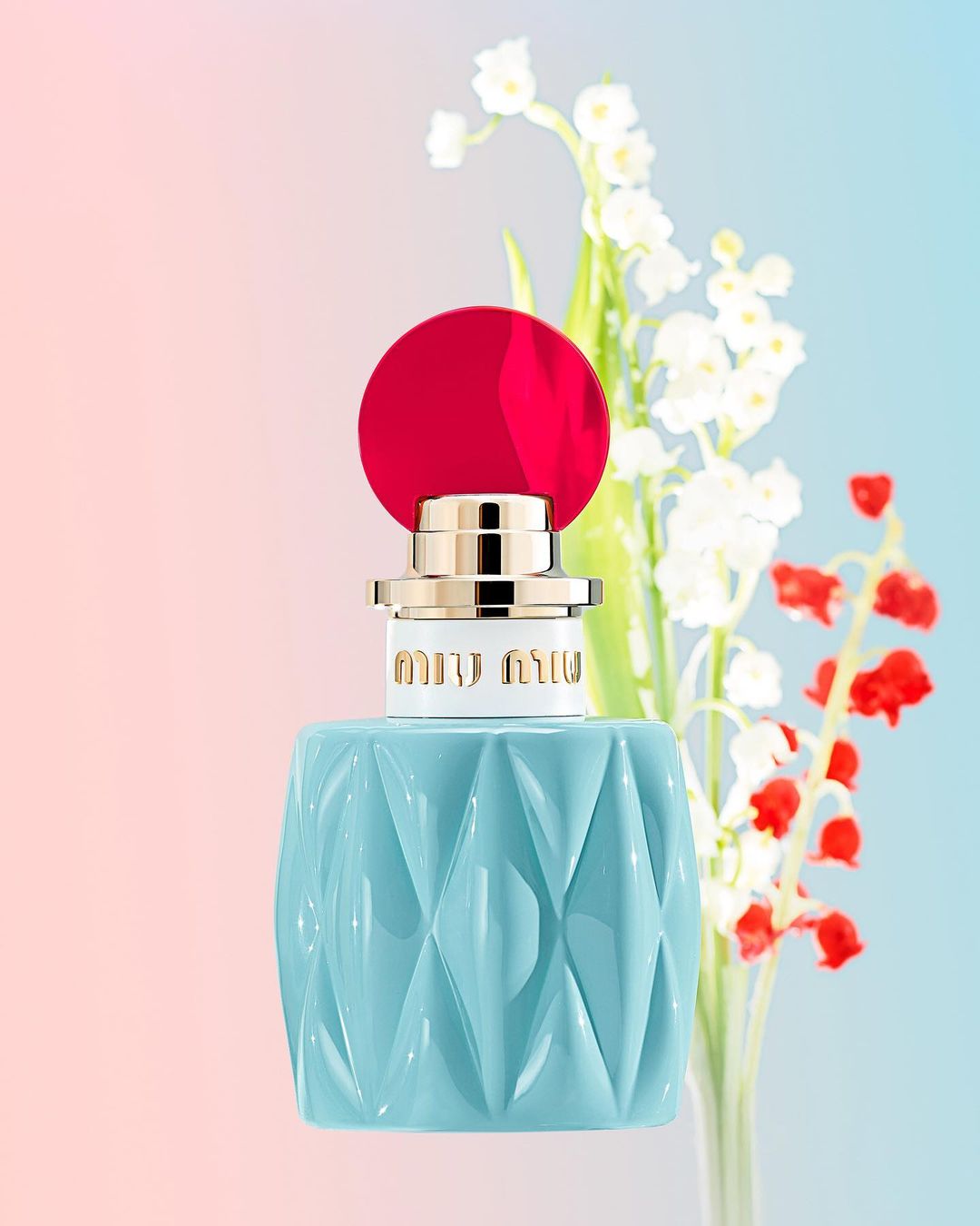 Miu Miu perfume bottle close-up on a gradient background with lily of the valley and red flowers, product shot for beauty and fashion.
