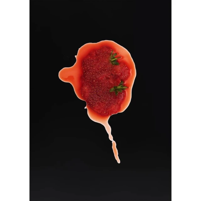 Overhead shot of strawberry puree with green sprigs on a black surface, offering a vibrant contrast of red and green.