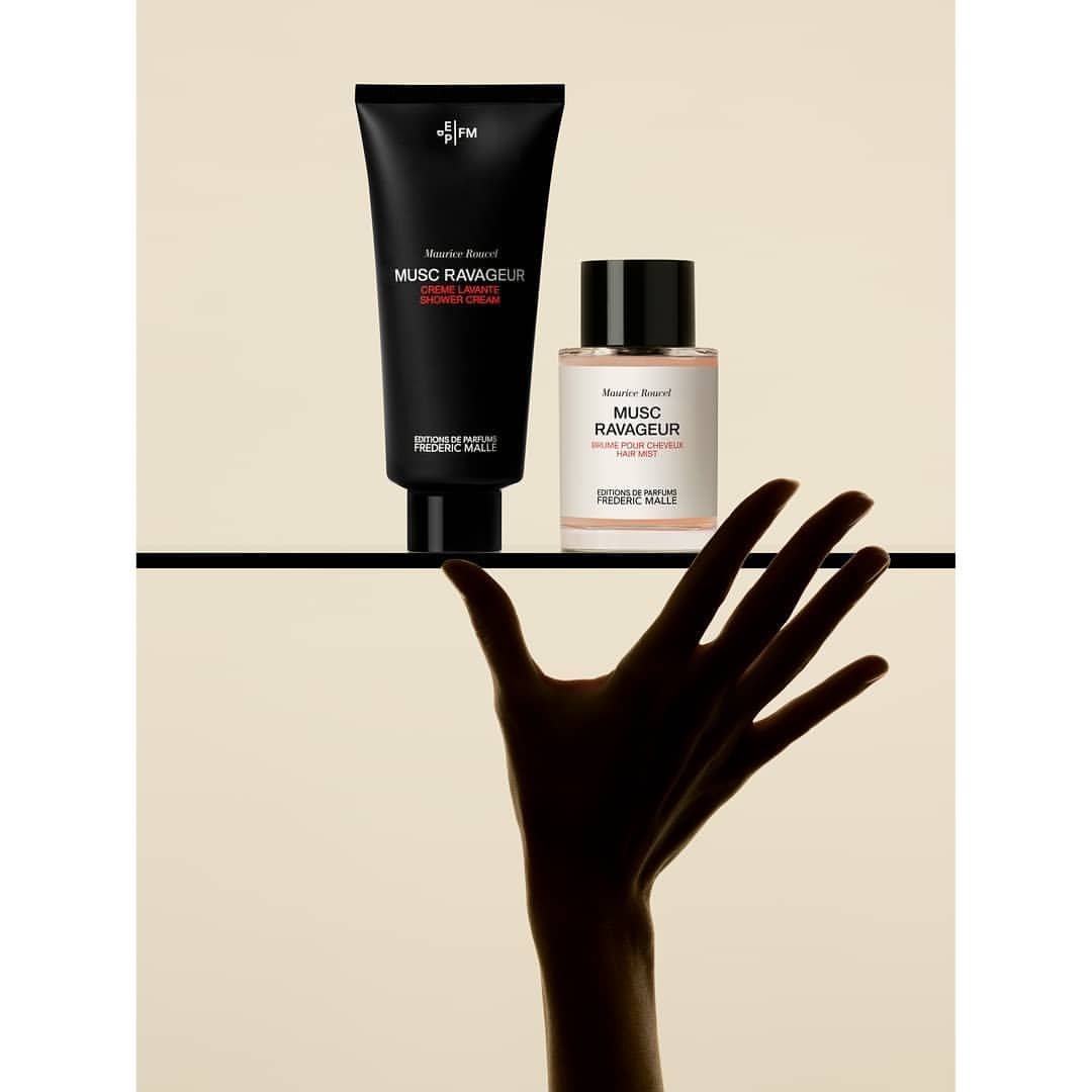 Frederic Malle Musc Ravageur product shot. Black shower cream tube and perfume bottle on shelf. Silhouette of reaching hand.