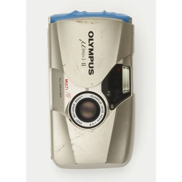 Silver Olympus [mju:]-II camera with a 35mm lens. Features include multi all-weather, large aperture. The camera sits on a white backdrop.