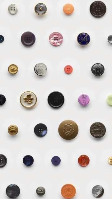 Collection of assorted buttons in varying sizes, colors, and designs arranged in a grid pattern on a clean white background.