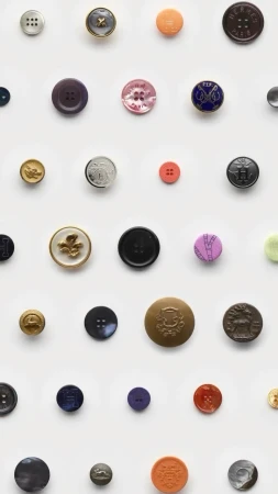 Collection of assorted buttons in varying sizes, colors, and designs arranged in a grid pattern on a clean white background.