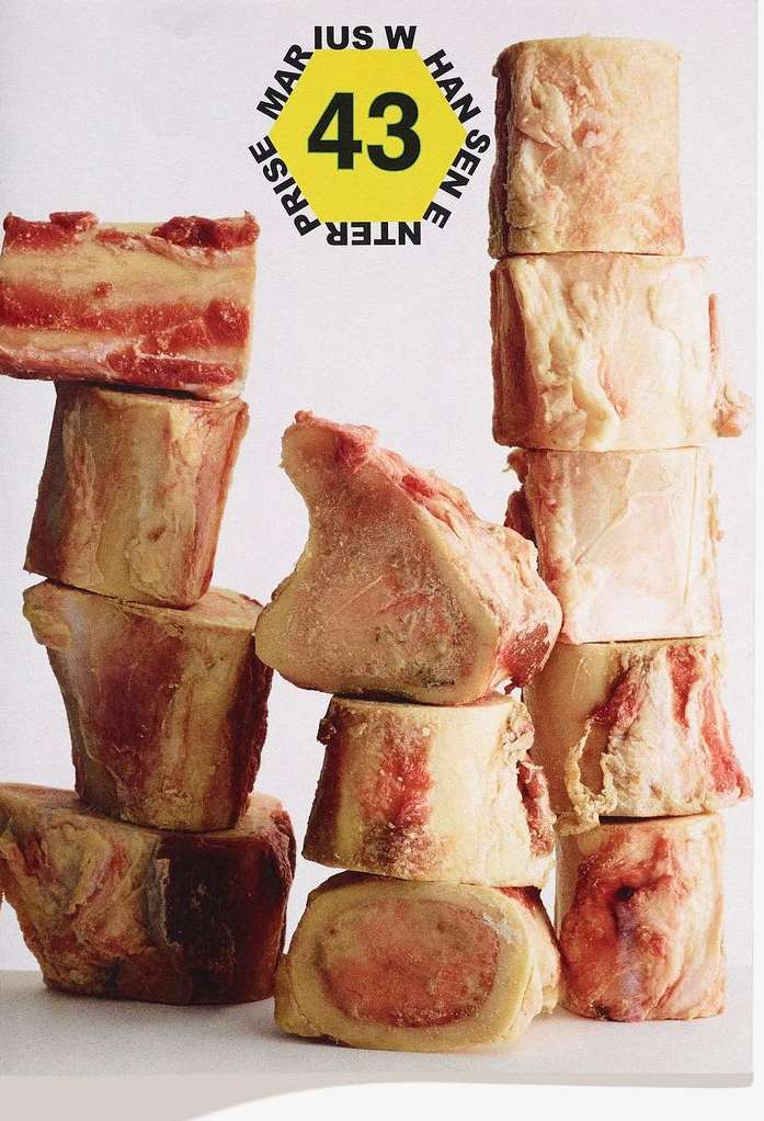 Stack of raw beef bone pieces, arranged in an artful pattern against a plain white backdrop, highlighting culinary elements and textures.