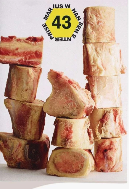 Stack of raw beef bone pieces, arranged in an artful pattern against a plain white backdrop, highlighting culinary elements and textures.