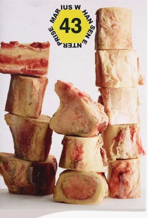 Stack of raw beef bone pieces, arranged in an artful pattern against a plain white backdrop, highlighting culinary elements and textures.